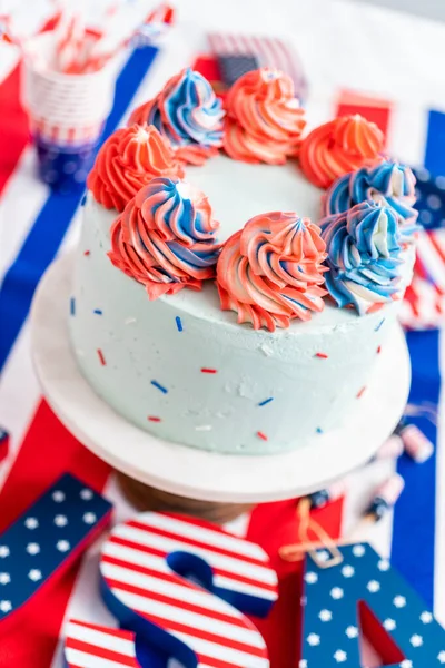 Red, white, and blue round vanilla cake with buttercream frosting for July 4th celebration.