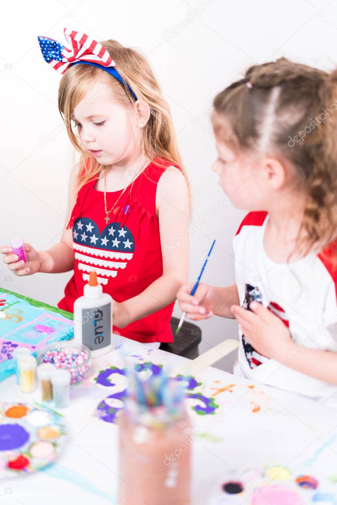 Little girls are painting on canvas on July 4th party.