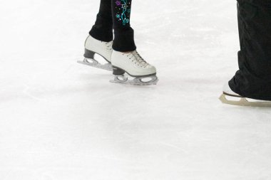 Artistik patinajda bir artistik patinajcı ve koçunun ayakları görülüyor..