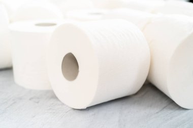 Gri arka planda yeni beyaz tuvalet kağıdı ruloları.