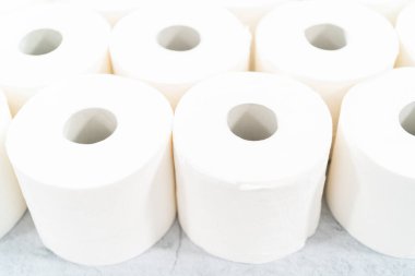Gri arka planda yeni beyaz tuvalet kağıdı ruloları.