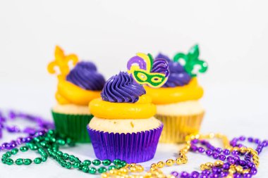 Mardi Gras vanilyalı kekler folyo kaplarda ve İtalyan tereyağlı kremayla süslenmiş..