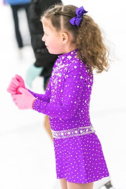 Küçük kız buz pateni pistinde artistik patinaj yapıyor..