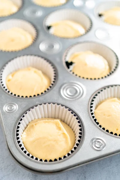 Vanilla cupcake batter in foil cupcake liners to bake Mardi Gras vanilla cupcakes.