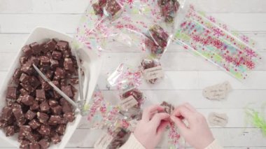 Düz yatıyordu. Adım adım. Ev yapımı macadamia şekerlemesi küçük hediye paketlerine konuyor..