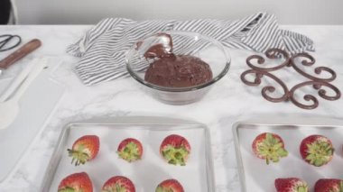 Adım adım. Çikolata kaplı çilek hazırlamak için organik çilekleri erimiş çikolatayla bir kaseye daldırmak..