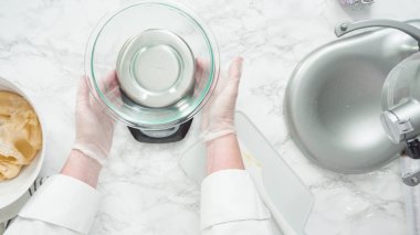 Adım adım. Düz yatıyordu. Kırmızı, beyaz ve mavi fırıldak şekerli kurabiyeler pişirmek için dijital mutfak terazisiyle ölçülmüş kurabiye..