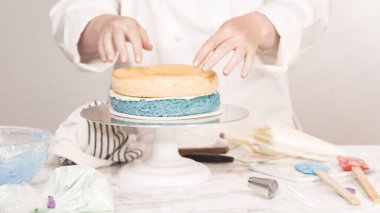 Yuvarlak üç katlı vanilyalı pasta yapmak için pasta katmanları yığılıyor.