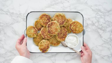 Düz yatıyordu. Adım adım. Beyaz metal tepside ekşi kremalı kabak kekleri..