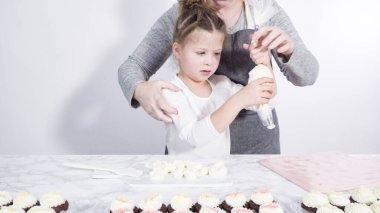 Adım adım. Küçük kız kesme tahtasına tereyağı kreması sürme alıştırması yapıyor.