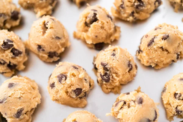 Homemade chocolate chip cookies dough scoops on a baking sheet.