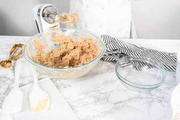 Mixing ingredients in a glass mixing bowl to bake chocolate chip cookies.