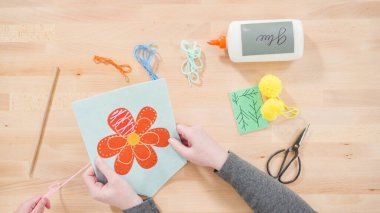 Küçük kız annesiyle el sanatları masasında dikiş dikmeyi öğreniyor..