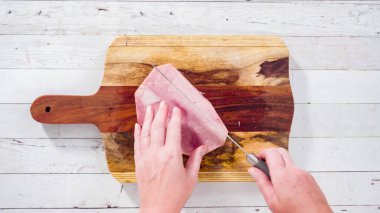 Düz yatıyordu. Ağaç kesme tahtasıyla organik ballı jambon kesmek.