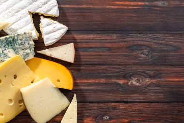 Düz yatıyordu. Koyu ahşap arka planda büyük gurme peynir dilimleri var..