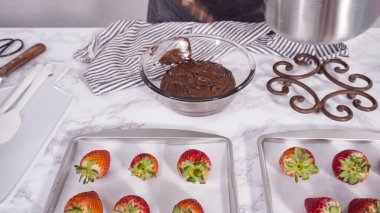 Adım adım. Çikolata kaplı çilek hazırlamak için organik çilekleri erimiş çikolatayla bir kaseye daldırmak..