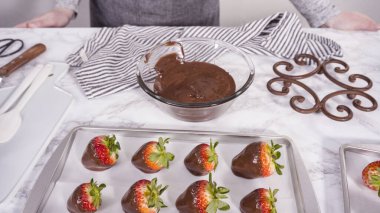 Adım adım. Çikolata kaplı çilek hazırlamak için organik çilekleri erimiş çikolatayla bir kaseye daldırmak..