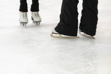 Artistik patinajda bir artistik patinajcı ve koçunun ayakları görülüyor..