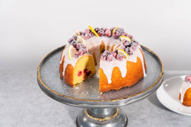 Dilimlenmiş limonlu kek. Şeker kızılcıkları ve limon dilimleri ile süslenmiş..