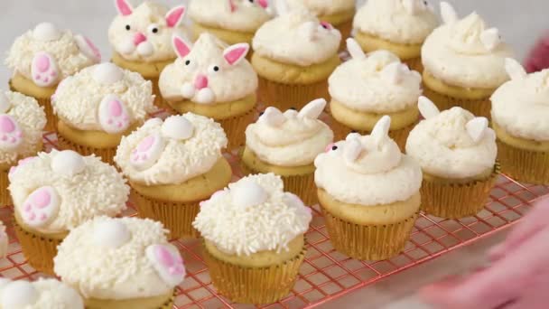 Flat lay. Decorating vanilla cupcakes with a white buttercream icing and bunny ears for Easter.