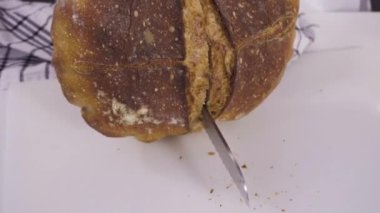 Beyaz bir kesme tahtasının üzerinde taze ekşi ekmek dilimliyorum..