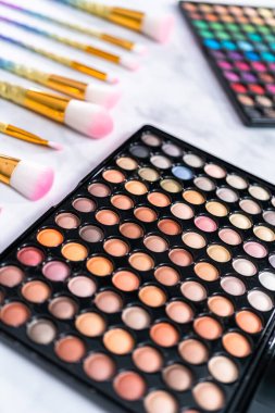 Mermer arka planda makyaj fırçaları olan yeni bir göz falı paleti.