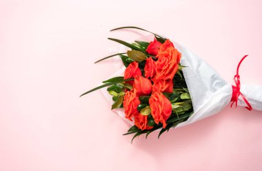 Düz yatıyordu. Kırmızı gül buketi ve pembe arka planda yeşil yapraklar..