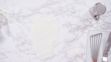 Düz yatıyordu. Adım adım. Mermer tezgahın üzerindeki beyaz fondanla kar tanelerini keserek..