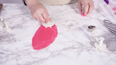 Adım adım. Mermer tezgahın üstünde pembe fondanla kar tanelerini keserek..