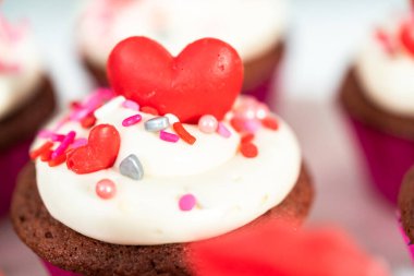 Krem peynirli kırmızı kadife kekler ve kalp ve öpücük şeklinde kırmızı çikolatalarla süslemeler..