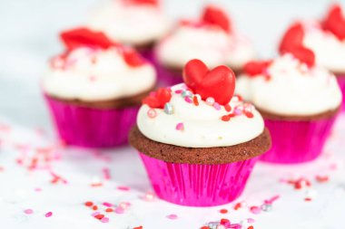 Krem peynirli kırmızı kadife kekler ve kalp ve öpücük şeklinde kırmızı çikolatalarla süslemeler..