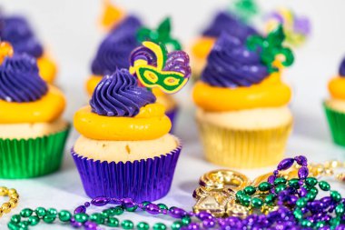 Mardi Gras vanilyalı kekler folyo kaplarda ve İtalyan tereyağlı kremayla süslenmiş..