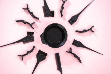 Düz yatıyordu. Siyah saç rengi boya seti ve pembe arka planda karıştırma kabı..