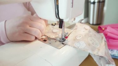 Koronavirüs salgını için dikiş makinesiyle pamuk yüz maskesi dikiyorum..