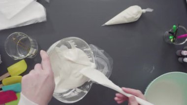 Tek boynuzlu at temalı vanilyalı kekleri süslemek için renkli krema kremalı boru torbaları hazırlanıyor..