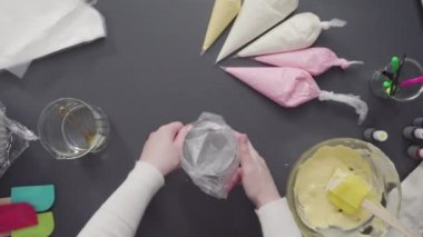 Tek boynuzlu at temalı vanilyalı kekleri süslemek için renkli krema kremalı boru torbaları hazırlanıyor..