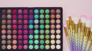 Beyaz arka planda tek boynuzlu at temalı makyaj fırçaları ve göz falı paleti.