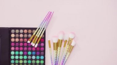 Beyaz arka planda tek boynuzlu at temalı makyaj fırçaları ve göz falı paleti.