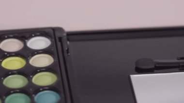 Beyaz arka planda tek boynuzlu at temalı makyaj fırçaları ve göz falı paleti.