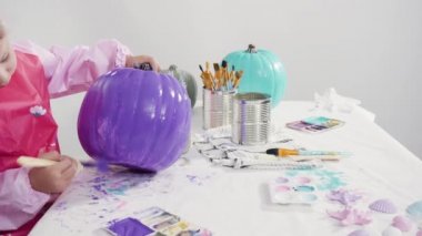 Küçük kız evde eğitim projesi için akrilik boyayla heykelcikler boyuyor..