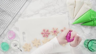 Kar taneleri şeklinde şekerli kurabiyeler ve pembe bir krema..