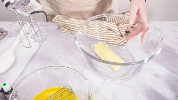 Step by step. Mixing ingredient in a mixing bowl with an electric mixer to bake vanilla Mardi Gras cupcakes.