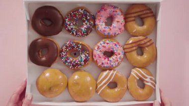 Beyaz bir karton kutuda mağazadan alınmış donutların çeşitliliği.
