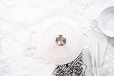 Düz yatıyordu. Beyaz mineli dökme demir bir Hollanda fırınında yemek pişirmek..