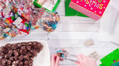 Düz yatıyordu. Adım adım. Ev yapımı macadamia şekerlemesi küçük hediye paketlerine konuyor..