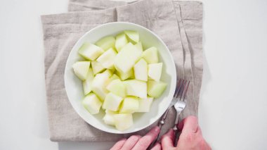 Adım adım. Düz yatıyordu. Beyaz kesme tahtasında kaygan altın çiğ taneli kavun.