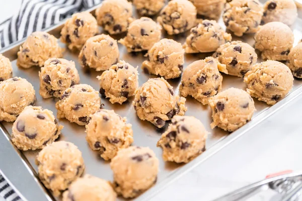 Homemade chocolate chip cookies dough scoops on a baking sheet.