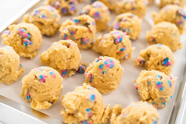 Chilled cookie dough scoops on the baking sheet to bake unicorn chocolate chip cookies.
