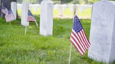 Denver, Colorado, ABD-26 Mayıs 2019 - Anma Günü 'nde Fort Logan Ulusal Mezarlığı' nda beyaz mermer mezar taşlarının yanında küçük Amerikan Bayrakları.