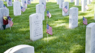 Denver, Colorado, ABD-26 Mayıs 2019 - Anma Günü 'nde Fort Logan Ulusal Mezarlığı' nda beyaz mermer mezar taşlarının yanında küçük Amerikan Bayrakları.